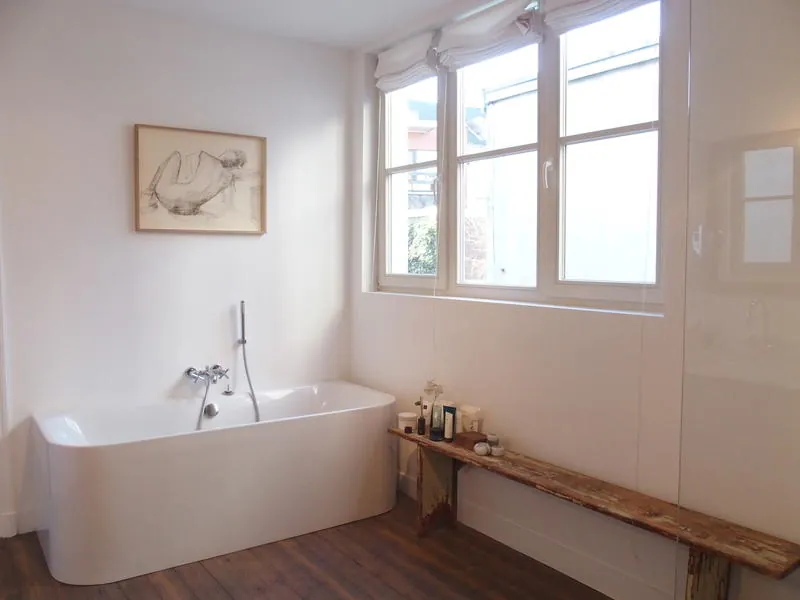 Badkamer met vrijstaand bad en een oude houten bank